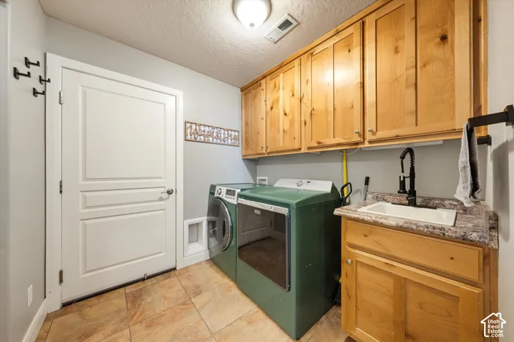 Laundry room featuring knotty pine cabinetry, a stone-pattern laminate countertop, an integrated drop-in utility sink with a high-arch matte black faucet, and ceramic tile flooring