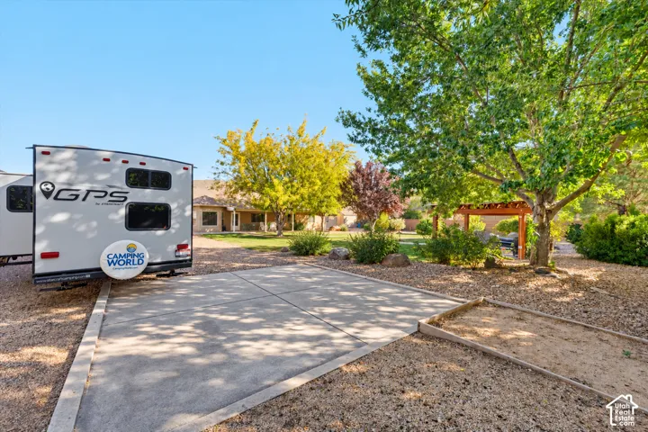 Concrete pad for recreational vehicle parking, xeriscaped grounds, mature trees, and a wooden pergola