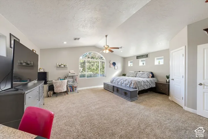 Vaulted ceilings, arched picture window, three transom windows, neutral wall palette, and integrated ceiling fan