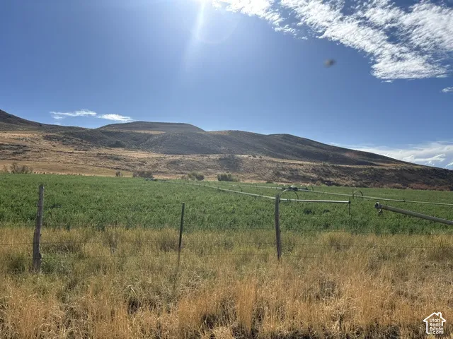 Expansive acreage featuring irrigated crop land, perimeter wire fencing, and mountain terrain