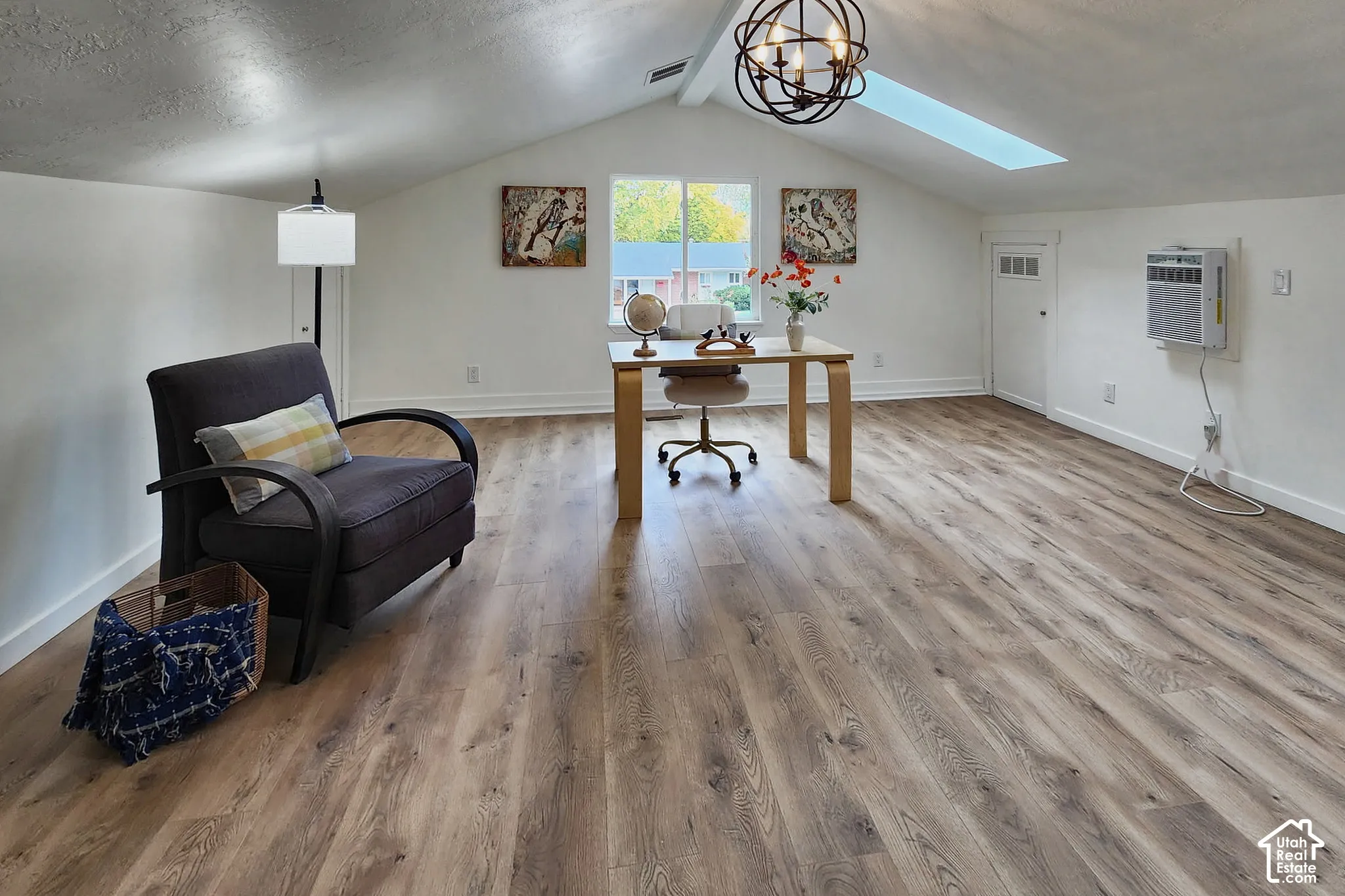 Vaulted ceilings with skylight, wood-finish flooring, and industrial-style spherical chandelier