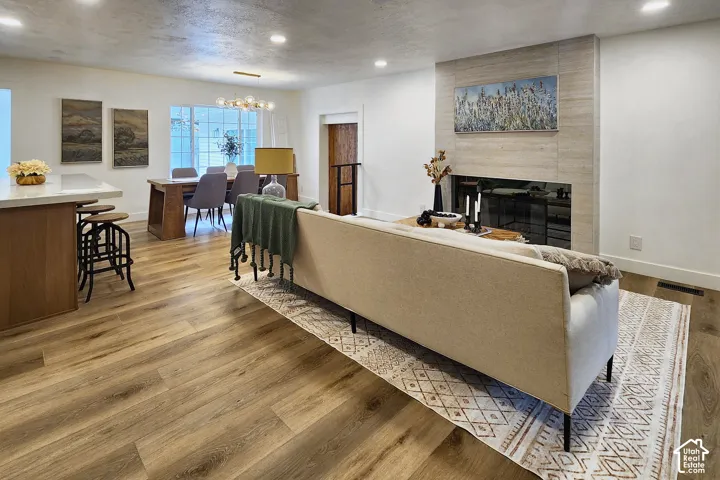 Open-concept interior featuring wood-finish flooring, recessed lighting, and a floor-to-ceiling fireplace surround with horizontal stonework