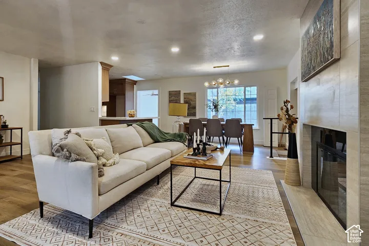 Fireplace featuring horizontal stone-tiled surround, wood-finish flooring, recessed lighting, and a multi-globe chandelier