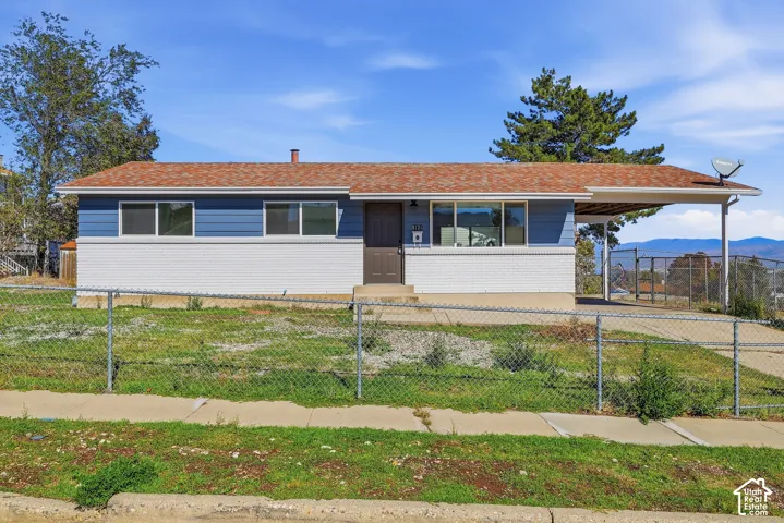 Single-story residence featuring a horizontal siding and brick facade, asphalt shingle roof, integrated carport, and expansive mountain terrain background