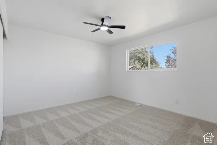 Neutral-toned wall-to-wall carpeting, modern ceiling fan with integrated LED lighting, and horizontal sliding window