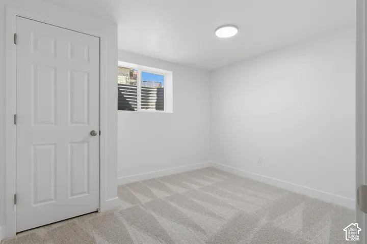 Neutral interior featuring wall-to-wall carpeting, a multi-panel interior door, a flush-mount ceiling light fixture, and an egress window