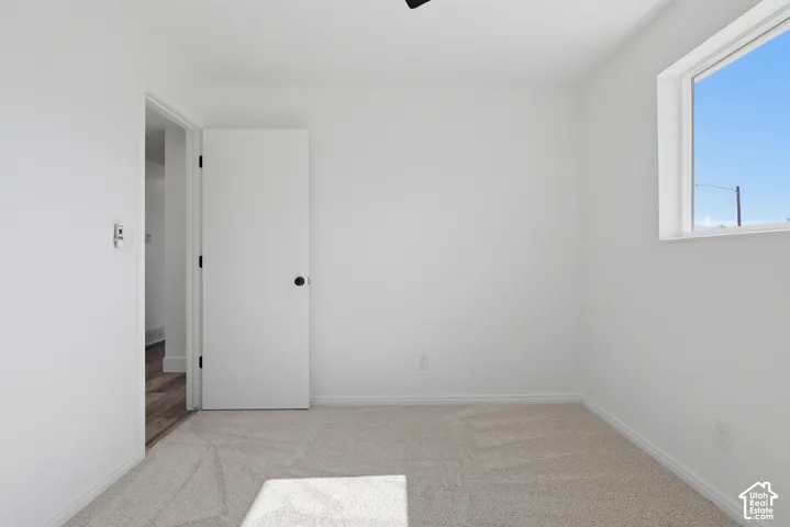 Neutral-toned carpet, solid-core interior door with matte black hardware, and an expansive window with natural light