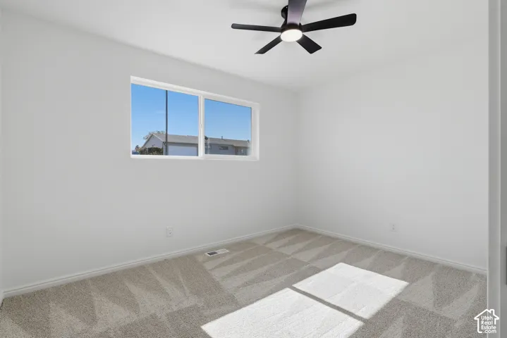 Neutral-toned wall-to-wall carpeting, matte black five-blade ceiling fan with integrated lighting, and horizontal sliding window