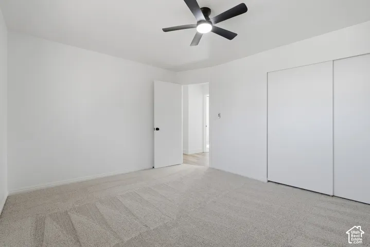 Neutral-toned carpeting, matte black ceiling fan with integrated lighting, and floor-to-ceiling sliding closet doors