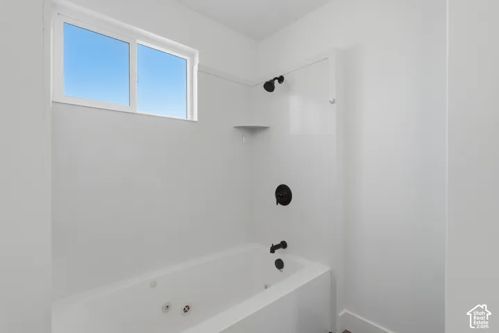 Jetted soaking tub with matte black hardware, integrated shelving, and a dual-pane horizontal sliding window