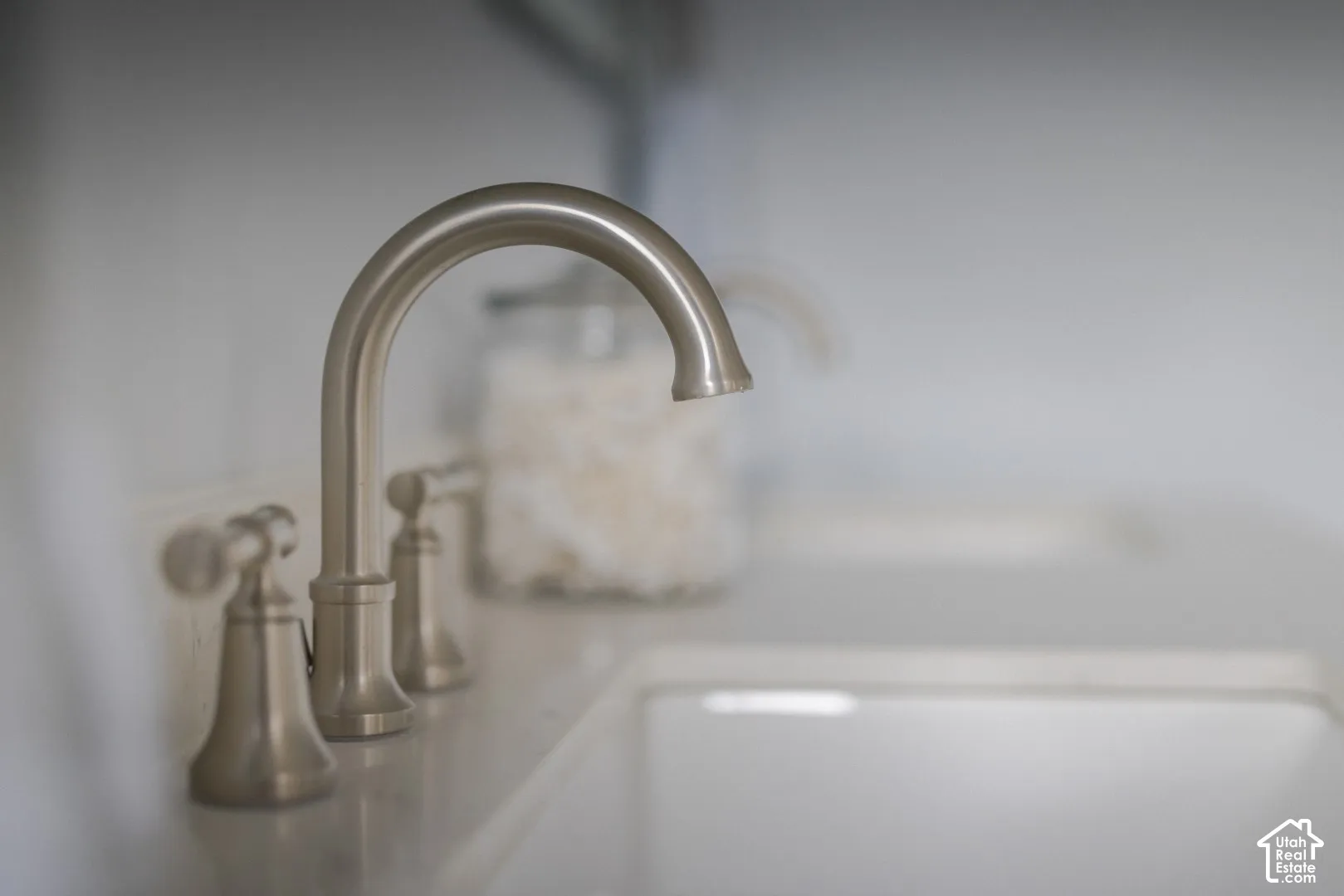 Brushed nickel widespread faucet featuring dual lever handles and a high-arc spout, paired with a white integrated basin and solid-surface countertop