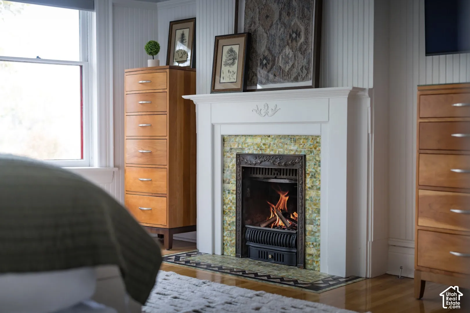 Fireplace featuring an ornate cast iron insert, decorative tile surround, and a traditional white mantle with detailed millwork, complemented by vertical tongue-and-groove wall paneling
