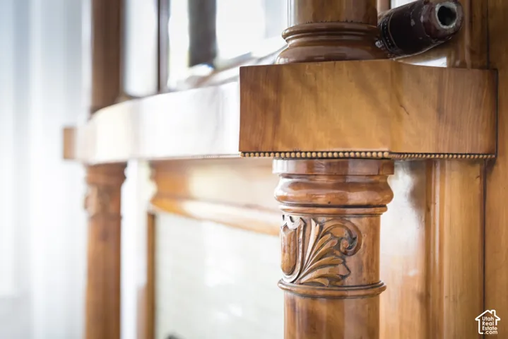 Wood fireplace mantel featuring intricate hand-carved column detailing, decorative beading, and a high-gloss finish