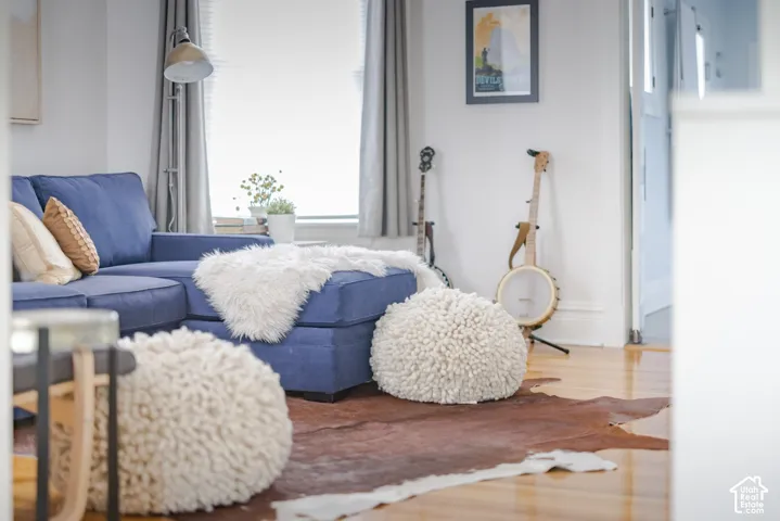 Neutral-toned interior space featuring light-toned wood-finish flooring, white walls, and a tall window with white casing