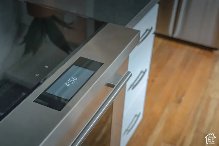 Stainless steel oven with digital touchscreen interface, white cabinetry with horizontal metal pulls, and wood-finish flooring