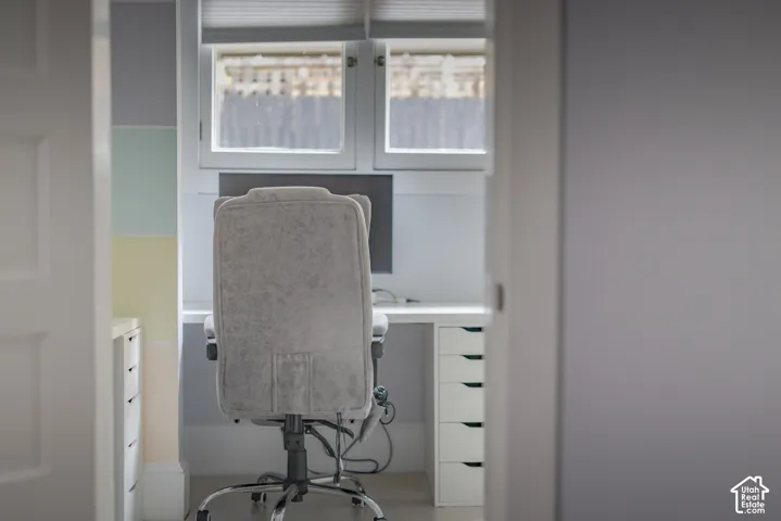 Built-in white cabinetry with multi-drawer storage, integrated desk surface, dual-pane windows, and cellular pleated window shades