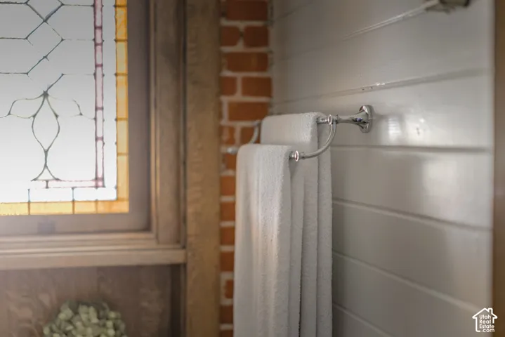 Stained glass window with wood casing, exposed brick wall detail, and horizontal plank wall paneling