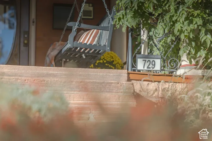 Covered front porch featuring stacked stone steps, decorative wrought iron railings, and a solid wood entry door with an oval glass inset