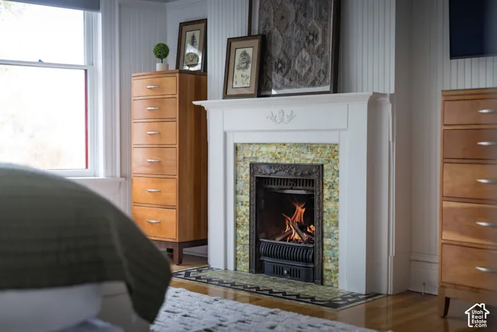 Fireplace featuring an ornate cast iron insert, decorative tile surround, and a traditional white mantle with detailed millwork, complemented by vertical tongue-and-groove wall paneling