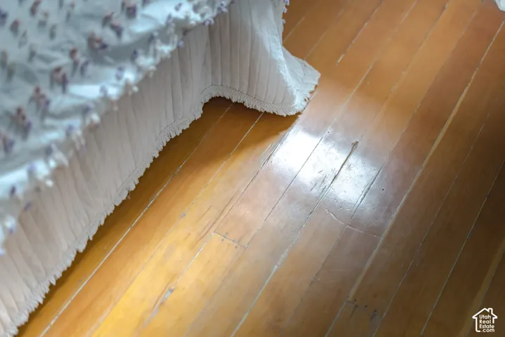 Hardwood flooring featuring a polished natural finish and narrow plank width