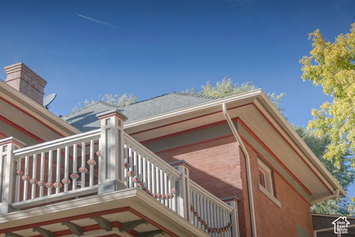 Exterior featuring multi-toned brick masonry, decorative balustrade with detailed newel posts, exposed rafter tails, and a shingled roofline