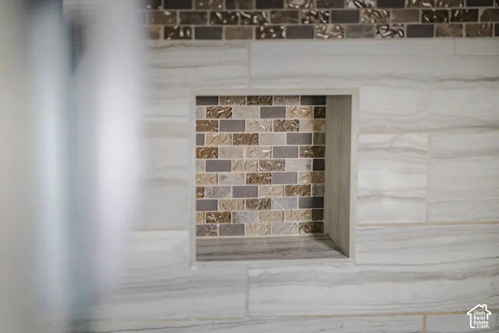 Recessed wall niche featuring multi-textured glass brick mosaic accents surrounded by large-format neutral tile