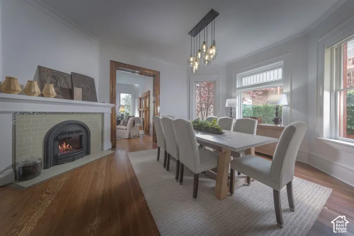 Fireplace with green tile surround and mantle, multi-pane transom windows, wood-finish flooring, and multi-bulb pendant lighting