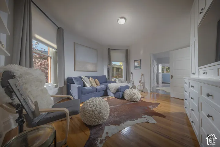 Living area featuring wood-finish flooring, white built-in cabinetry, dual window bays, and a multi-panel interior door