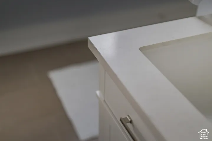 White vanity featuring an integrated countertop and basin with brushed nickel hardware
