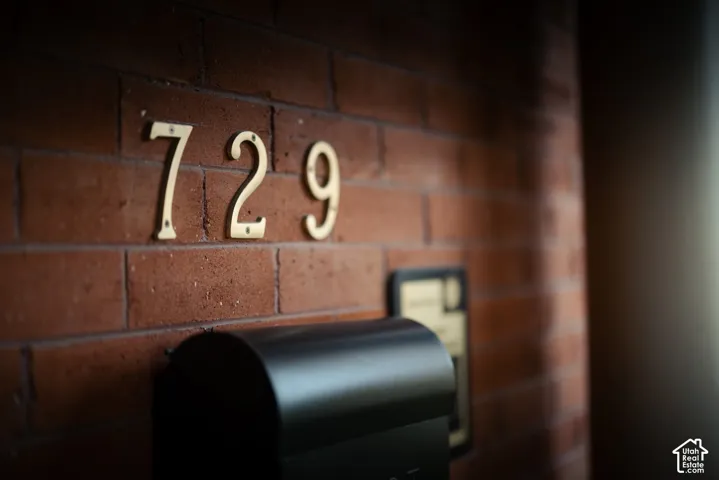 Exposed brick wall exterior featuring metallic house numbers and a black wall-mounted mailbox