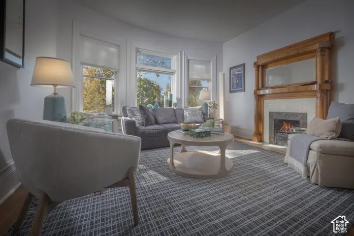 Bay window featuring stained glass detailing, wood-trimmed fireplace with built-in mantel mirror, and wood-finish flooring