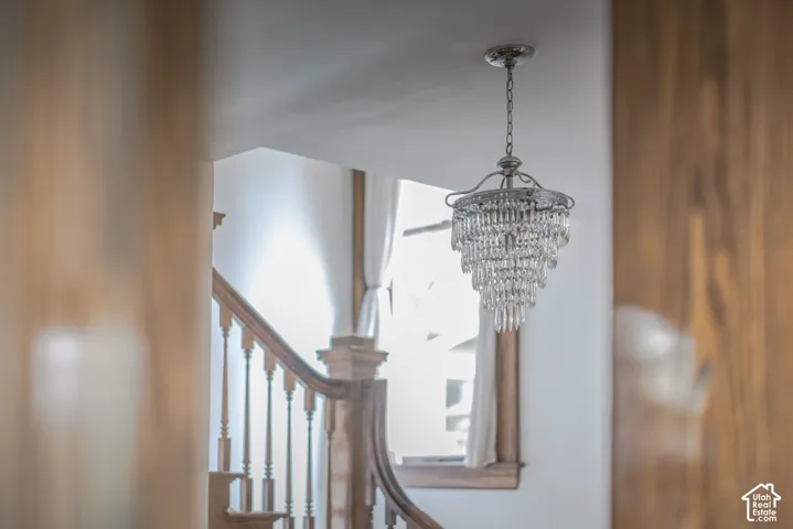 Multi-tiered crystal pendant lighting featuring a brushed-metal frame, wood-trimmed staircase, and decorative wood newel post
