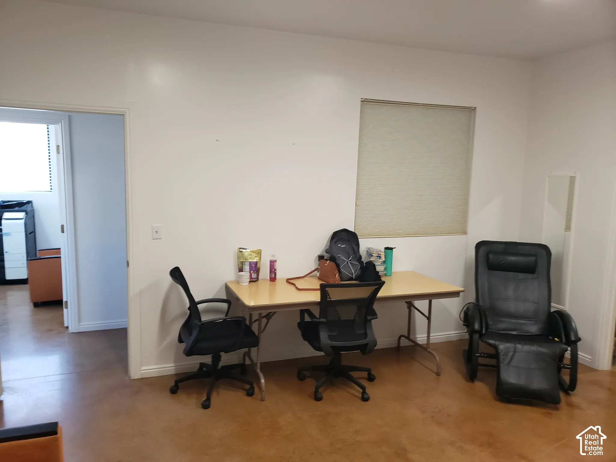 Interior room featuring stained concrete flooring, neutral wall tones, and a rectangular window fitted with an integrated roller shade