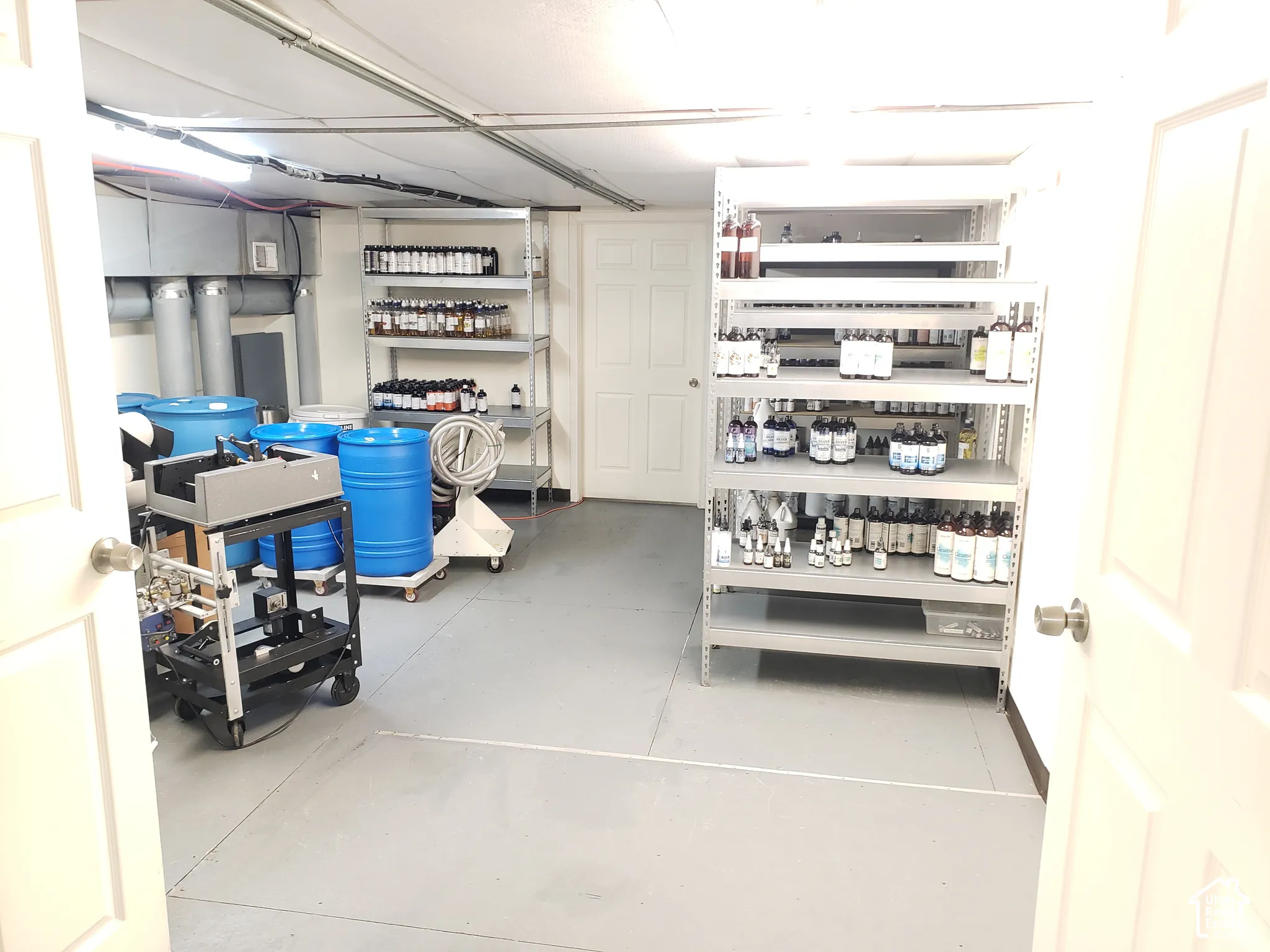 Utility room featuring durable painted concrete flooring, a six-panel door, and linear overhead lighting