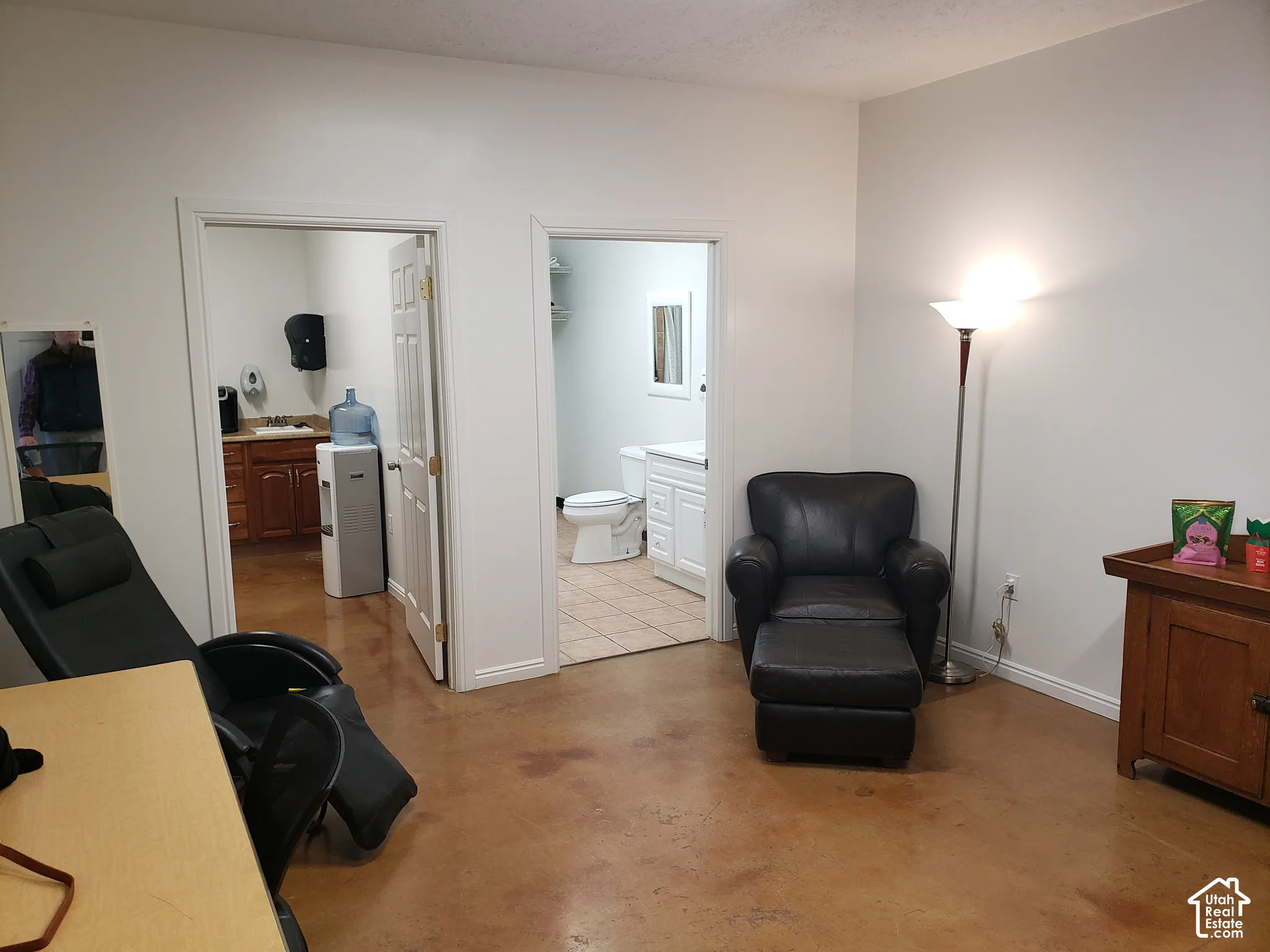 Polished concrete flooring, interior doorways with six-panel doors, and tile flooring within the restroom featuring a white vanity cabinet and commode