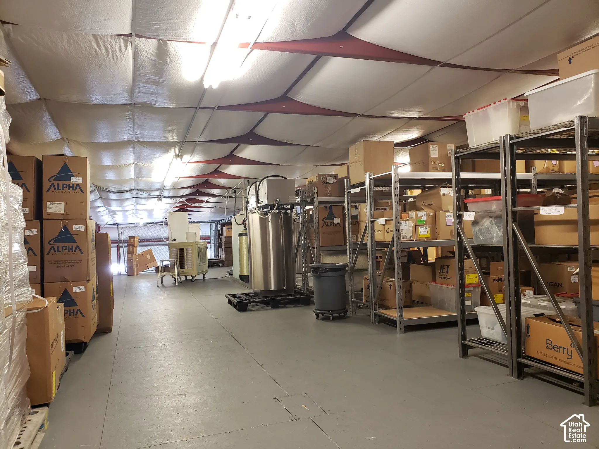 Industrial storage area featuring high ceilings with insulated paneling, durable concrete flooring, and overhead fluorescent lighting