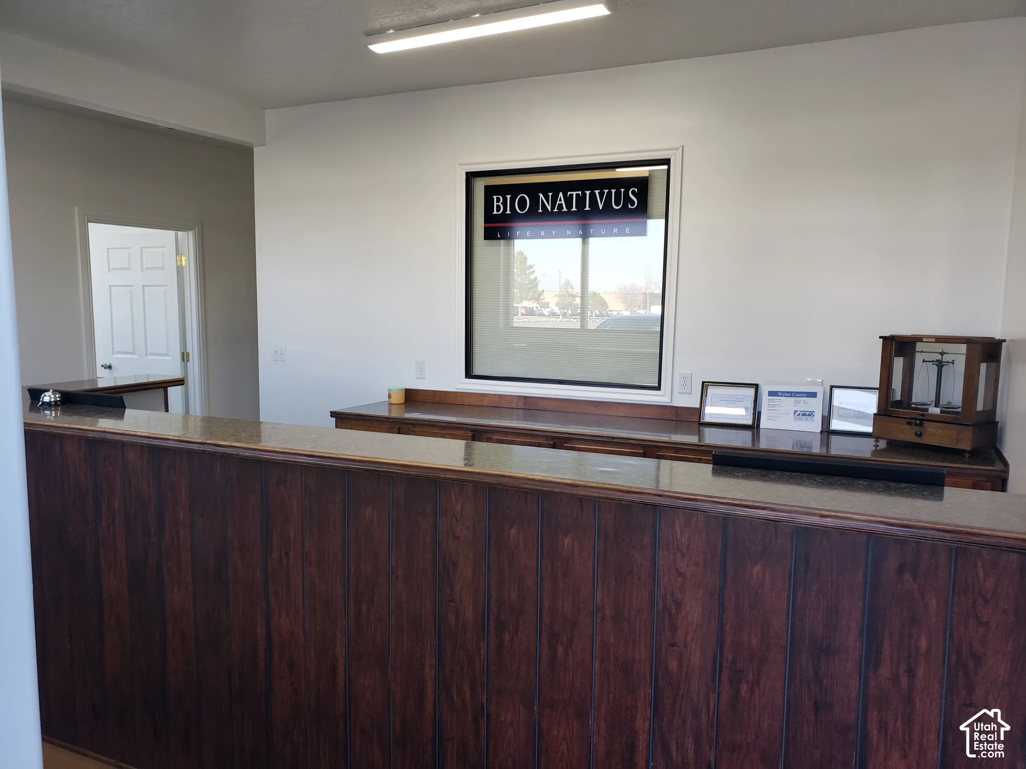 Reception area featuring a dark wood-paneled service counter with a stone-finish countertop, recessed window framing, and overhead linear lighting