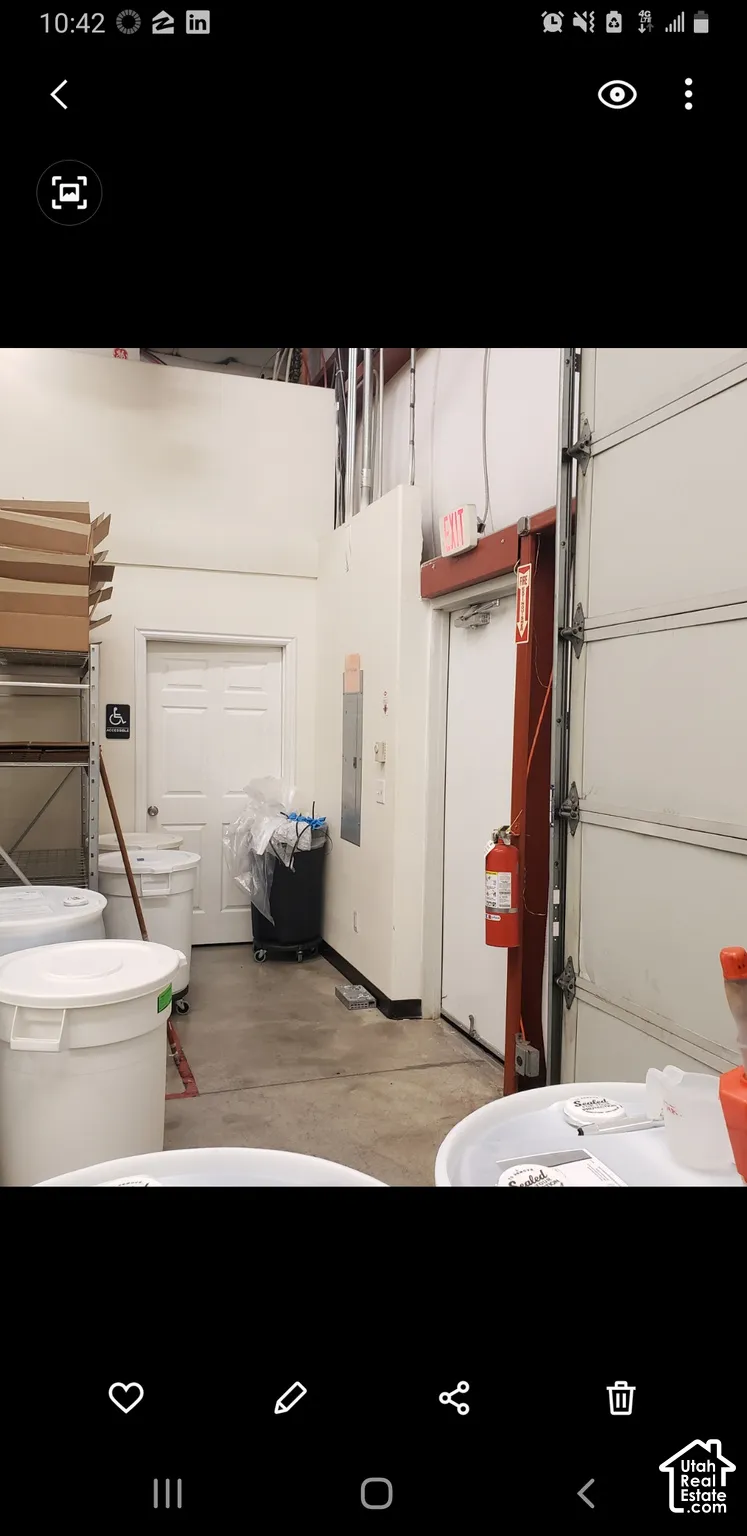 Industrial space featuring high ceilings, concrete flooring, a sectional roll-up door, and a built-in electrical service panel