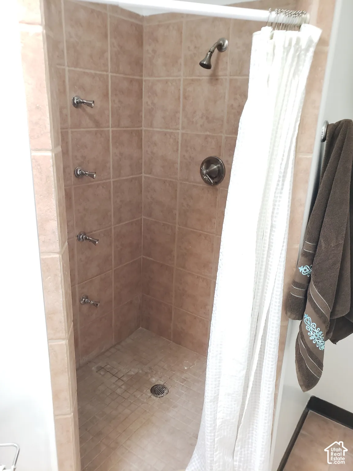Shower stall featuring floor-to-ceiling tile, four integrated wall-mounted water jets, and a single-handle faucet control