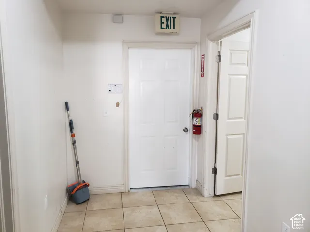 Interior space featuring light-colored tile flooring, white six-panel doors, and an illuminated exit sign