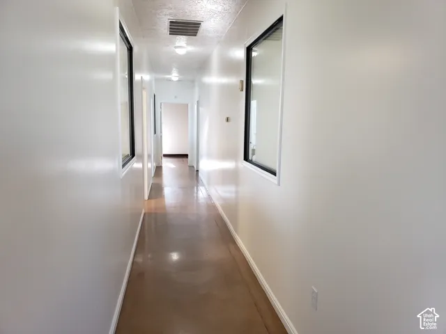 Hallway featuring polished concrete flooring, neutral wall finish, and two interior windows with black frames