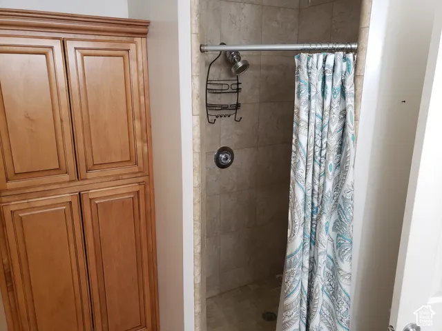 Built-in wooden cabinetry with raised-panel doors, tiled shower enclosure, and metallic shower hardware