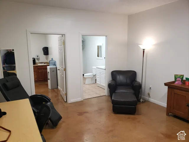 Polished concrete flooring, interior doorways with six-panel doors, and tile flooring within the restroom featuring a white vanity cabinet and commode