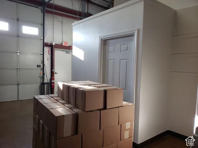 High-clearance sectional garage door, smooth-finished walls, and enclosed interior room with a six-panel door