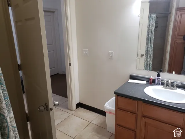 Bathroom vanity with wood-finish cabinetry, dark countertop, integrated oval sink, and large wall-mounted mirror