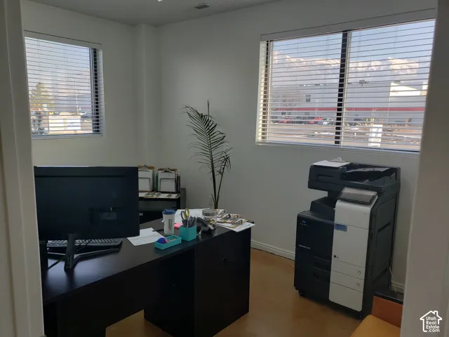 Neutral-toned interior featuring dual windows with horizontal blinds and concrete flooring