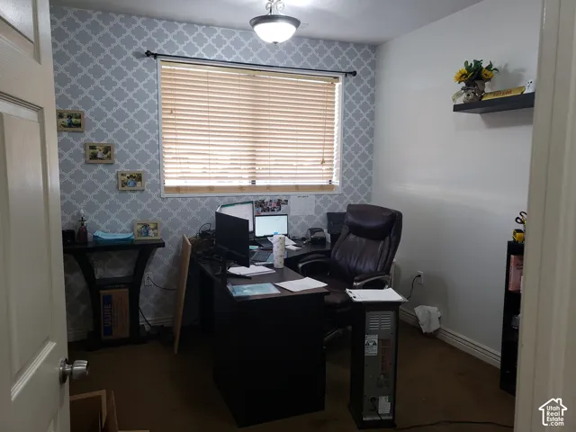Room featuring patterned wallpaper, a central window with slatted blinds, a flush-mount ceiling light fixture, and a built-in wall shelf