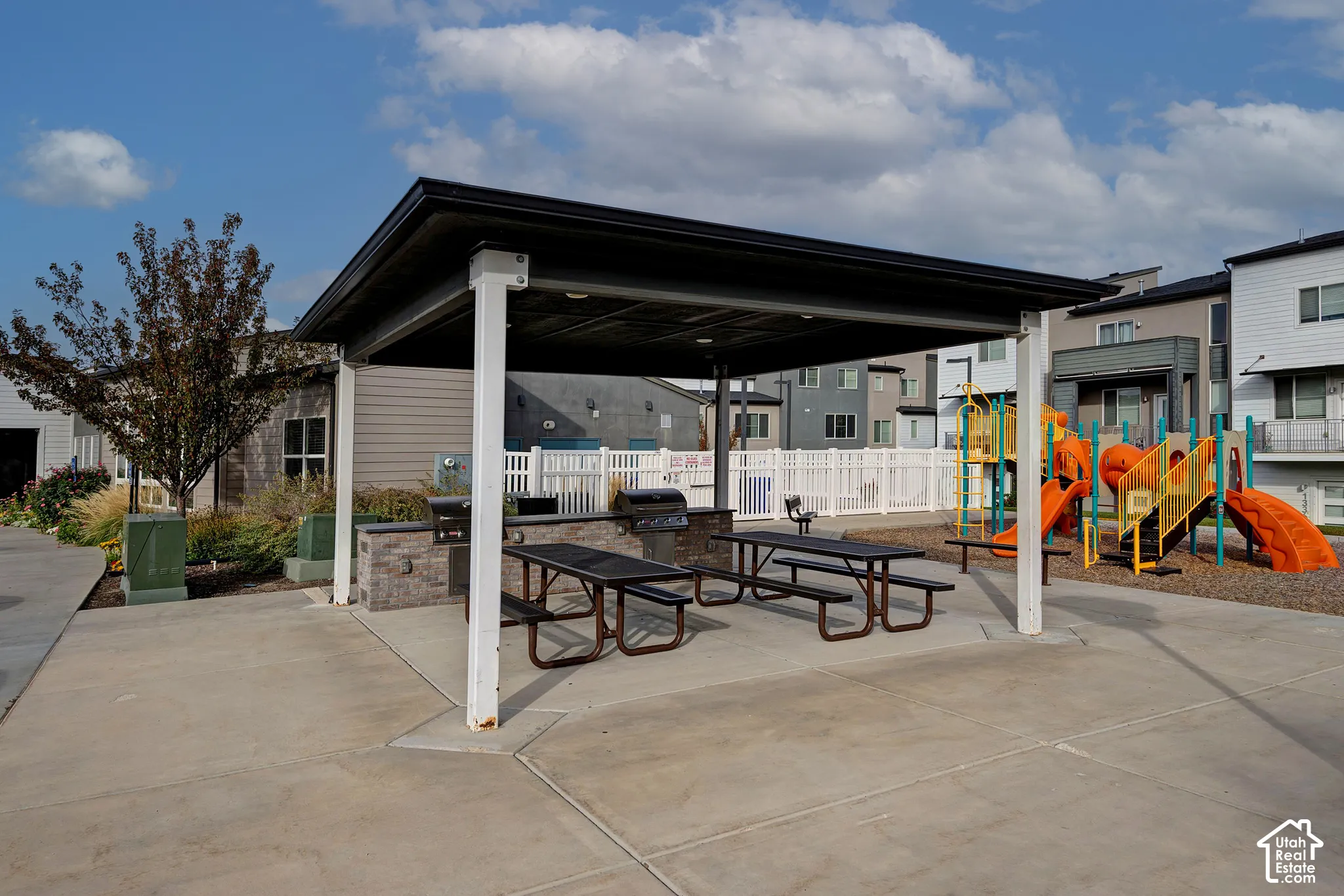 Covered outdoor pavilion featuring a stone-clad built-in grill and concrete patio space