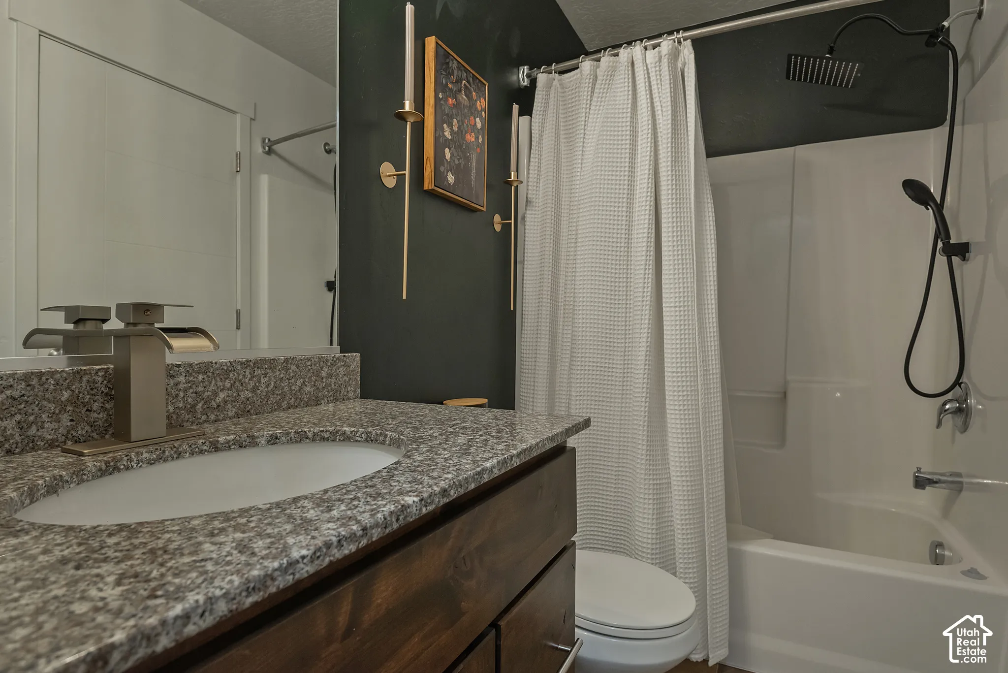 Bathroom vanity with stone-finish countertop, undermount sink, and metallic finish faucet, paired with a shower-tub combination featuring an overhead rainfall showerhead and a secondary handheld wand