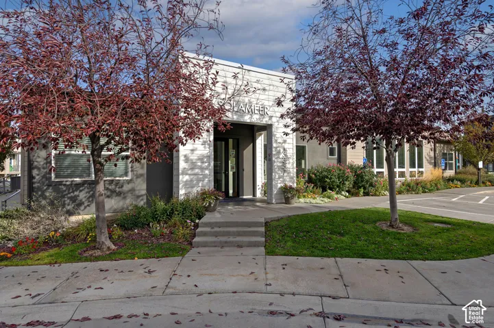 Exterior facade featuring horizontal white siding, dark grey accent walls, large multi-pane windows, and a paved concrete entryway with step access
